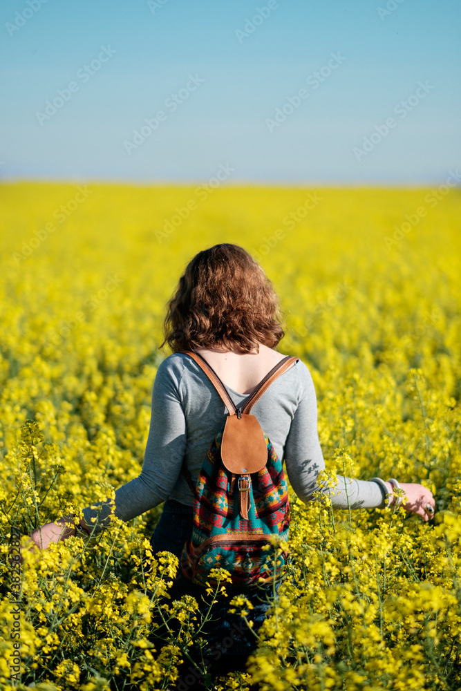 WomanWwith Backpack Walking Through The Field Of Yellow Flowers WomanWwith Backpack Walking Through The Field Of Yellow Flowers