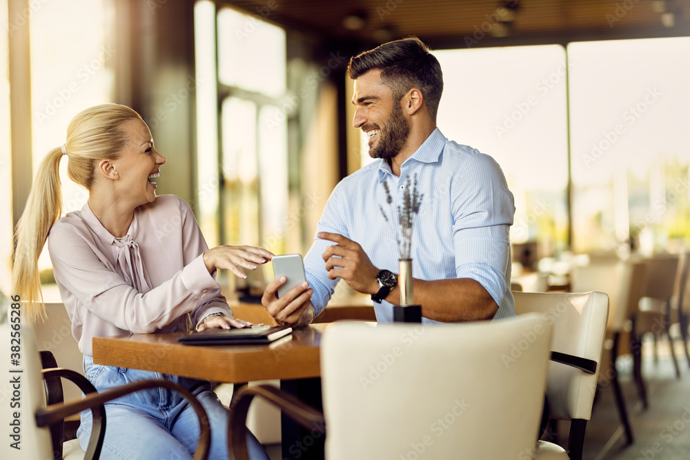 Cheerful couple having fun while using smart phone in a cafe, Cheerful couple having fun while using smart phone in a cafe,