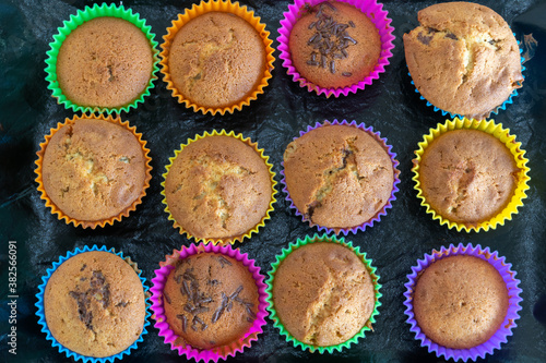 Obraz na płótnie Delicious pastry cooked at home. Homemade cupcakes in multi-colored silicone molds and with colored chocolates inside on a baking tray. w salonie