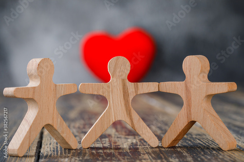 Business and insurance concept with wooden figures of people, red heart on wooden and foggy background close-up.