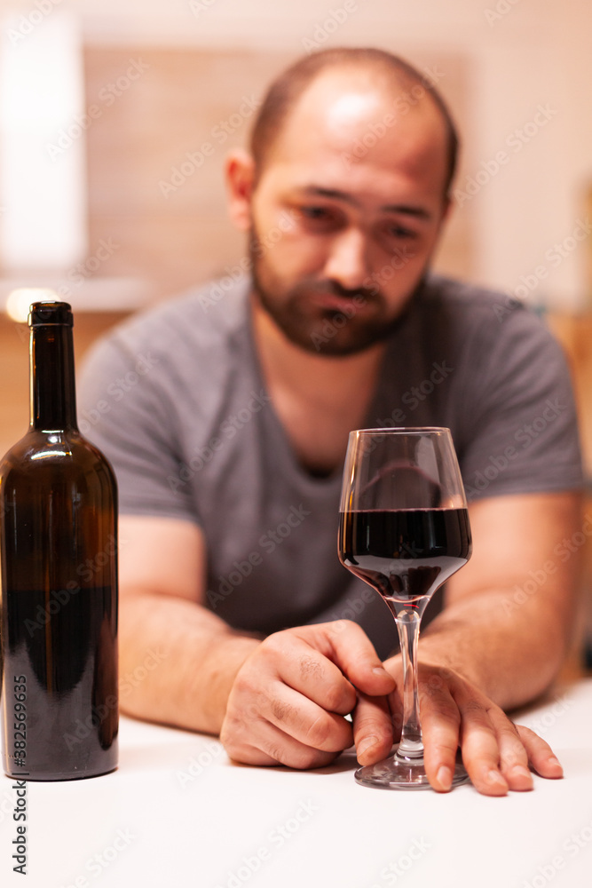 Man feeling wasted and emotional depressed after drinking glass of red wine. Unhappy person disease and anxiety feeling exhausted with having alcoholism problems.
