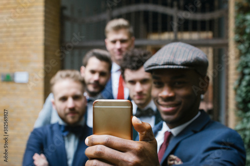 Young Black Man Taking Selfie of Five Smiling Friends in Suits