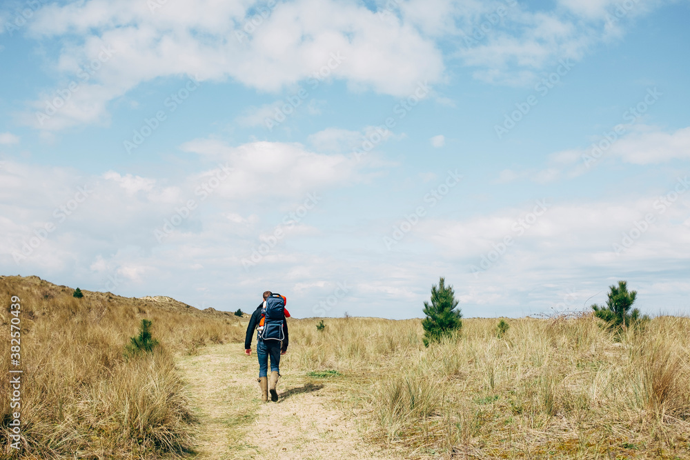 Young father walking on the coast with his daughter in a baby carrier backpack. Norfolk, UK. Young father walking on the coast with his daughter in a baby carrier backpack. Norfolk, UK.