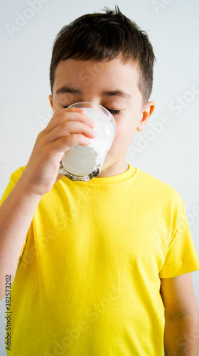 Adorable boy with glass of milk or kefir on white background.