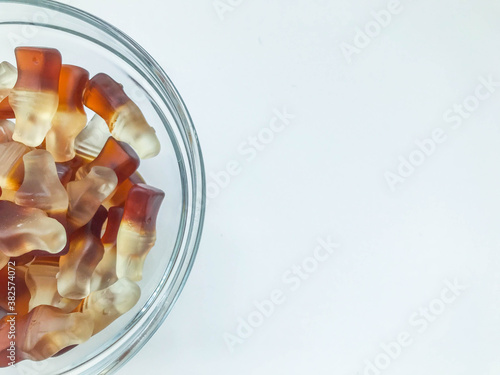 the bottle-shaped marmalade is in a small, round and transparent plate. gelatinous mouth-watering sweets. macro photography, an unusual angle. children's sweets and treats photo