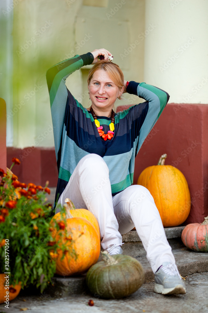 Fototapeta premium mature woman on the porch of a house with columns in autumn