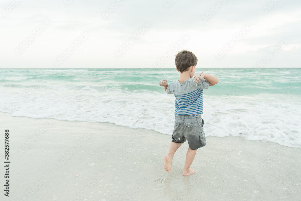 A Boy Throwing Sand Into The Water A Boy Throwing Sand Into The Water
