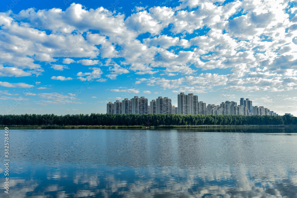 Fototapeta premium Blue sky and white clouds in the background of waterfront city skyline scenery, LUANNAN COUNTY, Hebei Province, China.