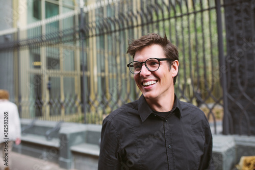 Portrait of a young man with glasses and a black shirt, smiling. photo