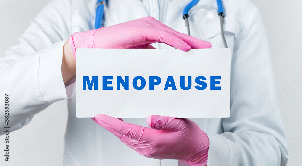 Cropped view of young female doctor holding a card with text MENOPAUSE. Medical concept Cropped view of young female doctor holding a card with text MENOPAUSE. Medical concept