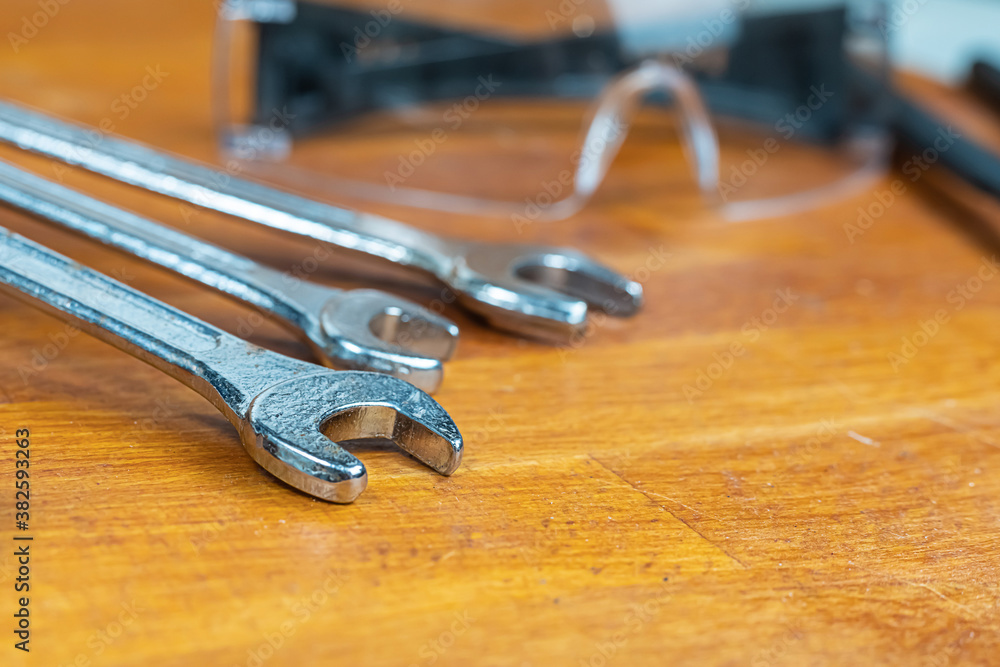 set of iron wrenches lie on a blurred background of safety glasses set of iron wrenches lie on a blurred background of safety glasses