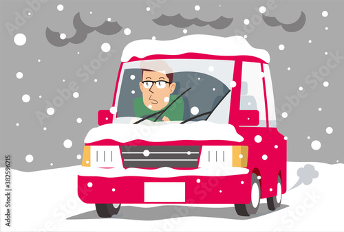 大雪の道を心配そうにドライブする男性