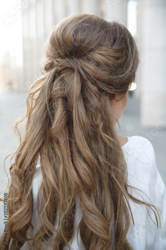 Elegant hairstyle on long blond hair, seen from the back outside.