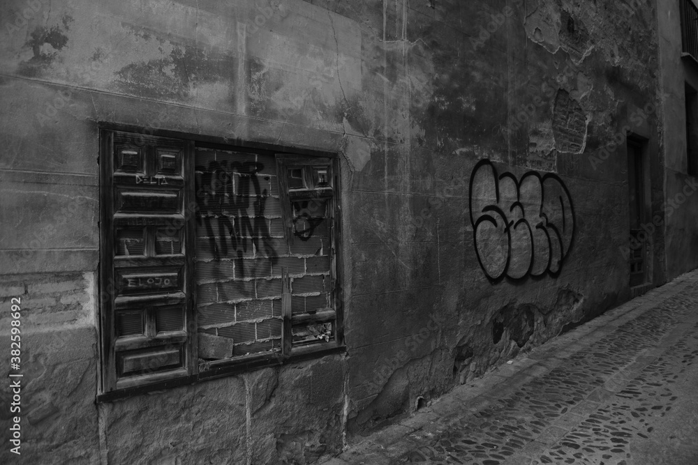 Bricked up window and graffiti on a city street in black and white