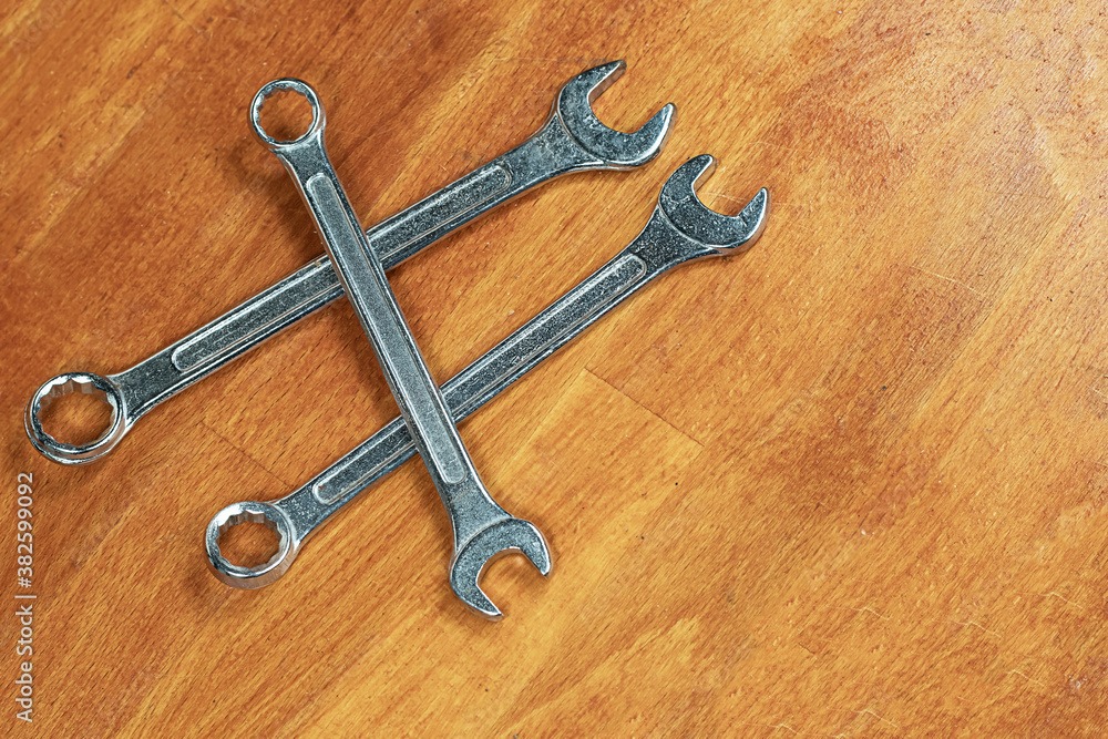 three iron chrome wrenches lie in a heap on a wooden background three iron chrome wrenches lie in a heap on a wooden background