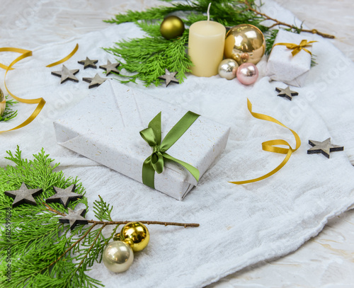 Geschenk zu Weihnachten mit Tannengrün, goldene Christbaumkugeln, Kerze, Sternen und Kerze