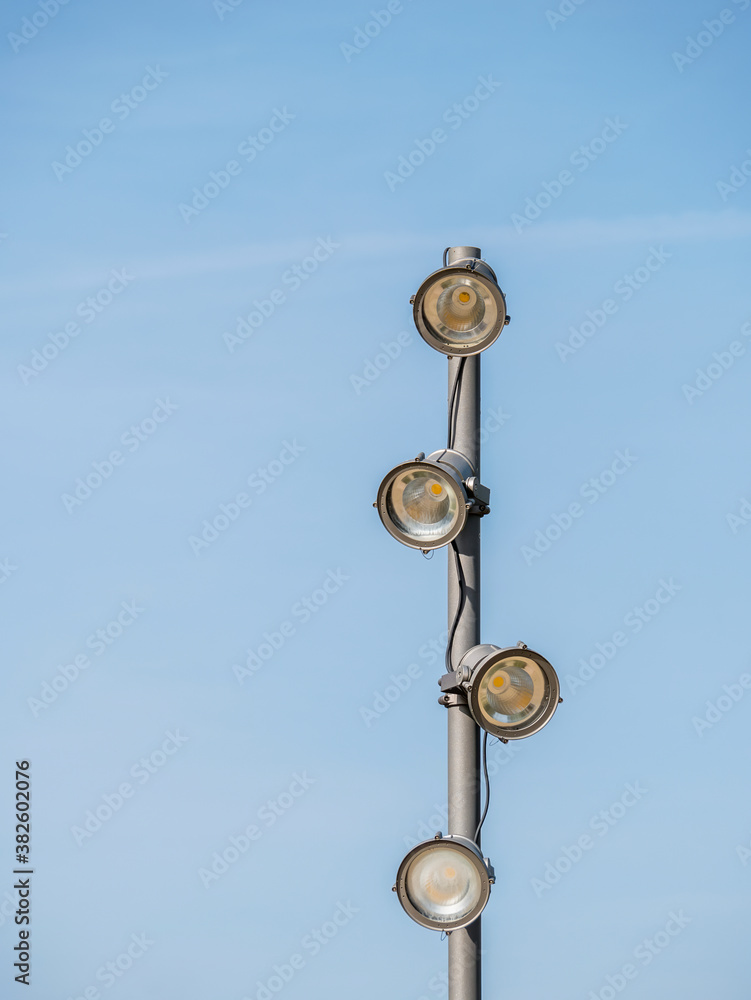 Metal pole with spot lights or bulb lights against clear blue sky. Led lamp with directional light Metal pole with spot lights or bulb lights against clear blue sky. Led lamp with directional light