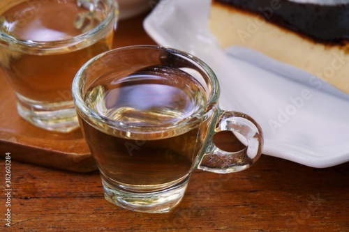 Gray wormwood herbal tea in a glass cup, dry sagebrush flowers in spoon, fresh flowers in a mortar and on table against dark wooden board photo