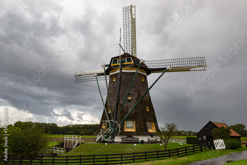Dutch windmill in a rural landscape on a rainy day under a dark cloudy sky