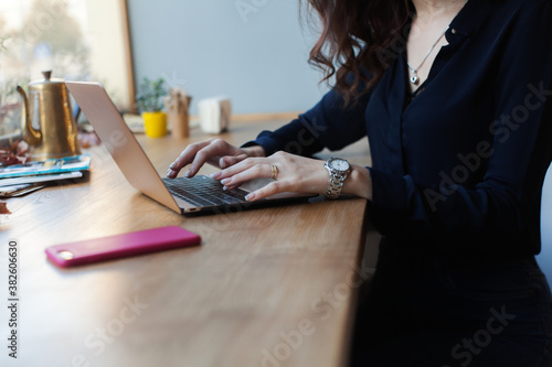 Portrait of young woman using laptop at cafe, she is working on laptop computer at a coffee shop. (ID: 382606630)