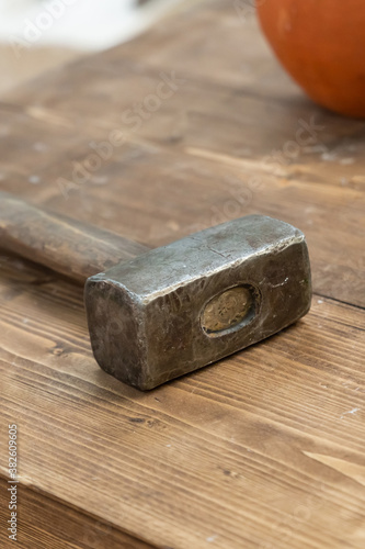 old metal and heavy hammer builder's work tool or forge on wooden table