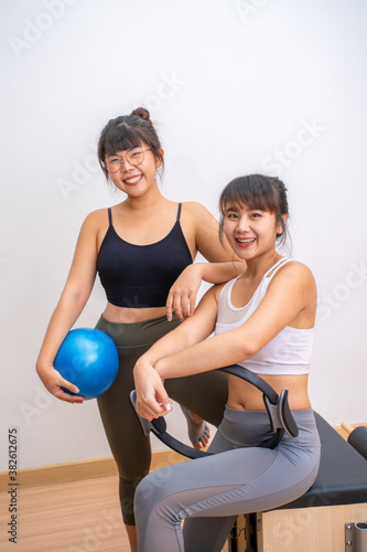 Two young happy Asian women posing and smiling for camera during their exercise break