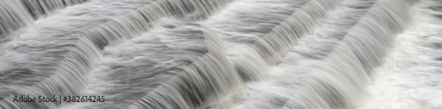 White Water flowing over weir low-level view at long exposure to give blurred motion effects