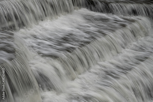 White Water flowing over weir low-level view at long exposure to give blurred motion effect