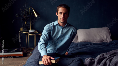 young man with a book is sitting on the bed, a portrait © Ulia Koltyrina