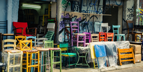 Multiple colorful chairs outside graffitied store in Athens, Greece