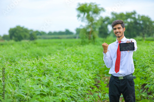 Technology and people concept  Young indian agronomist showing tablet at field