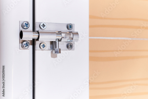 manual latch with metal pin and screws installed in an aluminum carpentry door inside a house photo