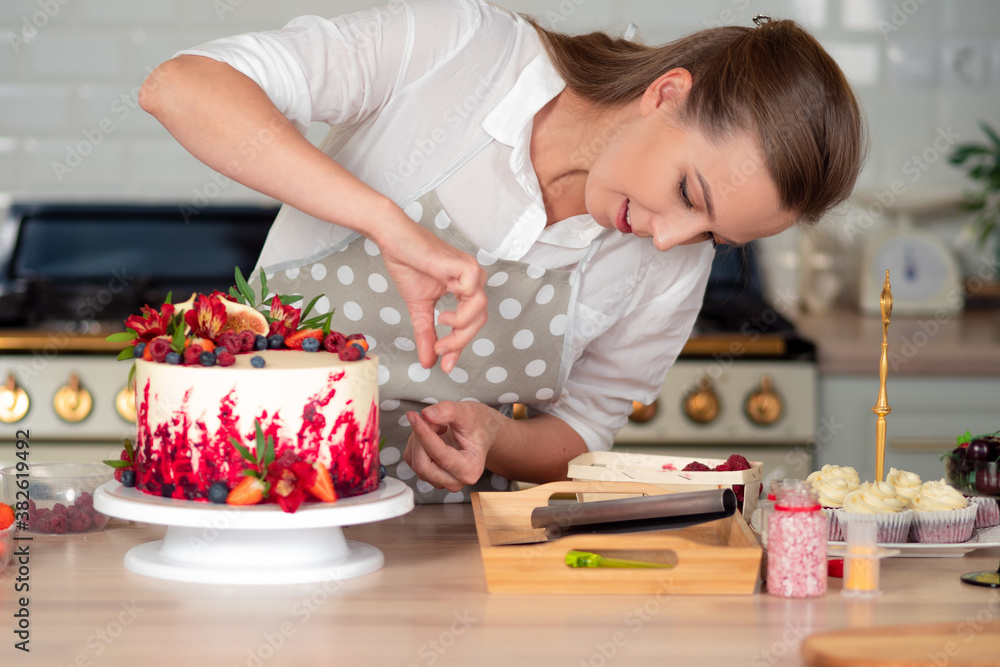 cooking and decoration of cake with cream. Young woman pastry chef in the kitchen decorating red velvet cake cooking and decoration of cake with cream. Young woman pastry chef in the kitchen decorating red velvet cake