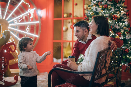 Family with a child near a New Year tree in Christmas decorations