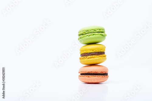 Macaroni, red, yellow and green, are stacked one on top of the other in the form of a tower on a white background. Side view
