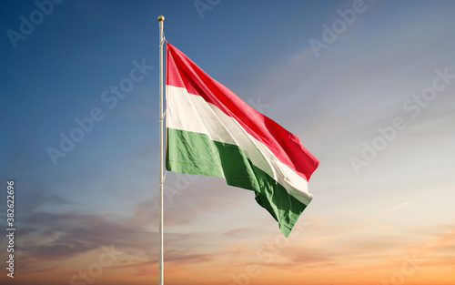 Beautiful flags of Hungary waving against blue cloudy sunset sky background. Hungarian national flag. © Leo Altman