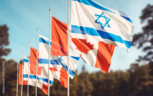 Canada and Israel flags waving at forest background. Concept of international Canadian Israeli relations. photo