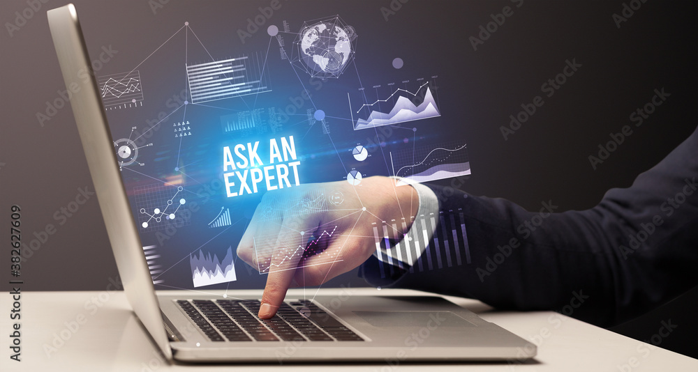 Businessman working on laptop with ASK AN EXPERT inscription, new business concept Businessman working on laptop with ASK AN EXPERT inscription, new business concept