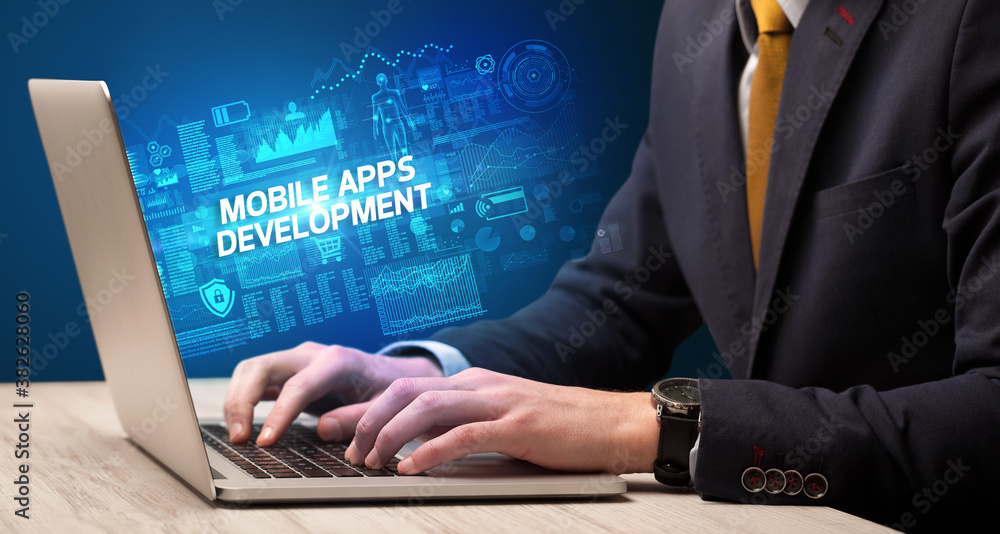Businessman working on laptop with MOBILE APPS DEVELOPMENT inscription, cyber technology concept Businessman working on laptop with MOBILE APPS DEVELOPMENT inscription, cyber technology concept