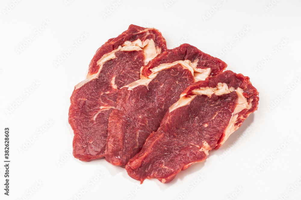Obraz premium Three raw beef steaks on white background