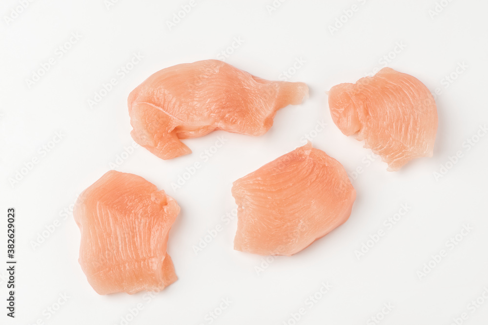 Fototapeta premium Top view on pieces of raw chicken fillet on white background