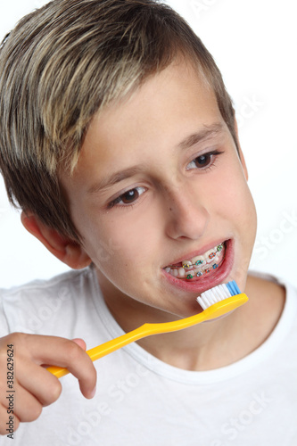 oy brushing his teeth with a toothbrush and looking at the camera isolated on white background