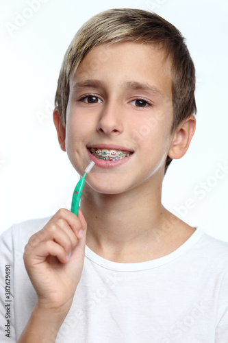 Boy with braces smiling while brushing your teeth