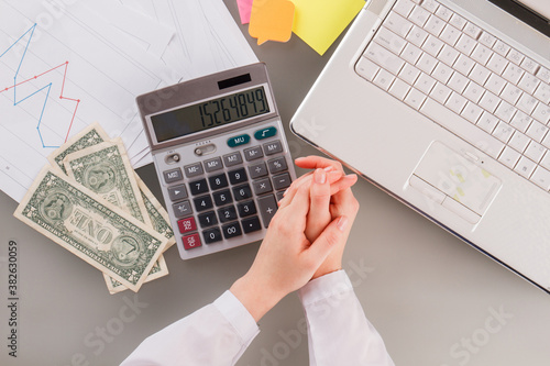 Female hands, calculator, money and laptop on office desk. Concept of finance and accounting.