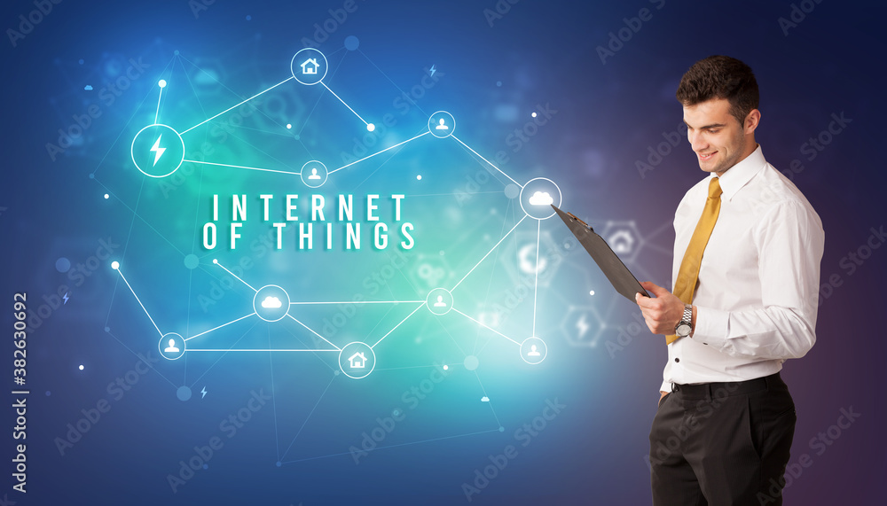 Businessman in front of cloud service icons with INTERNET OF THINGS inscription, modern technology concept Businessman in front of cloud service icons with INTERNET OF THINGS inscription, modern technology concept
