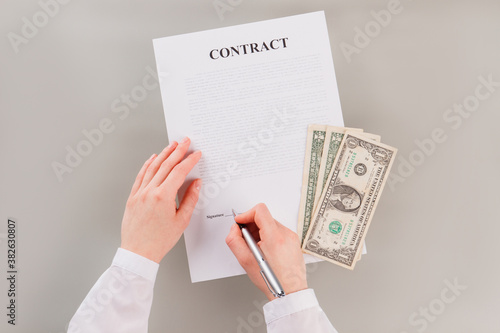 Woman is signing a contract to get a lot of money. Bribe for signing contract.