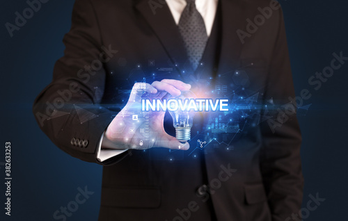 Businessman holding light bulb with INNOVATIVE inscription, innovative technology concept