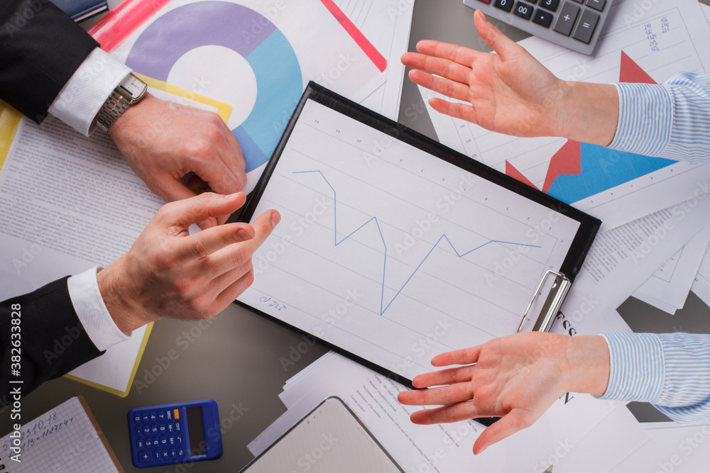 Business people discussing business and financial report. Two business partners or coworkers analyzing a financial graph and company budget during a meeting in office. Business people discussing business and financial report. Two business partners or coworkers analyzing a financial graph and company budget during a meeting in office.