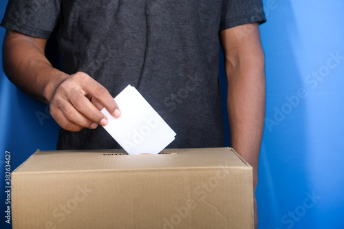 Close up of man's hand putting card in box with slot,