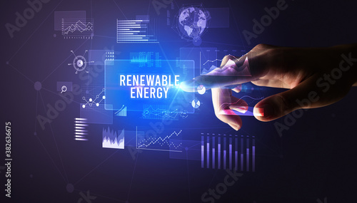 Hand touching RENEWABLE ENERGY inscription, new business technology concept